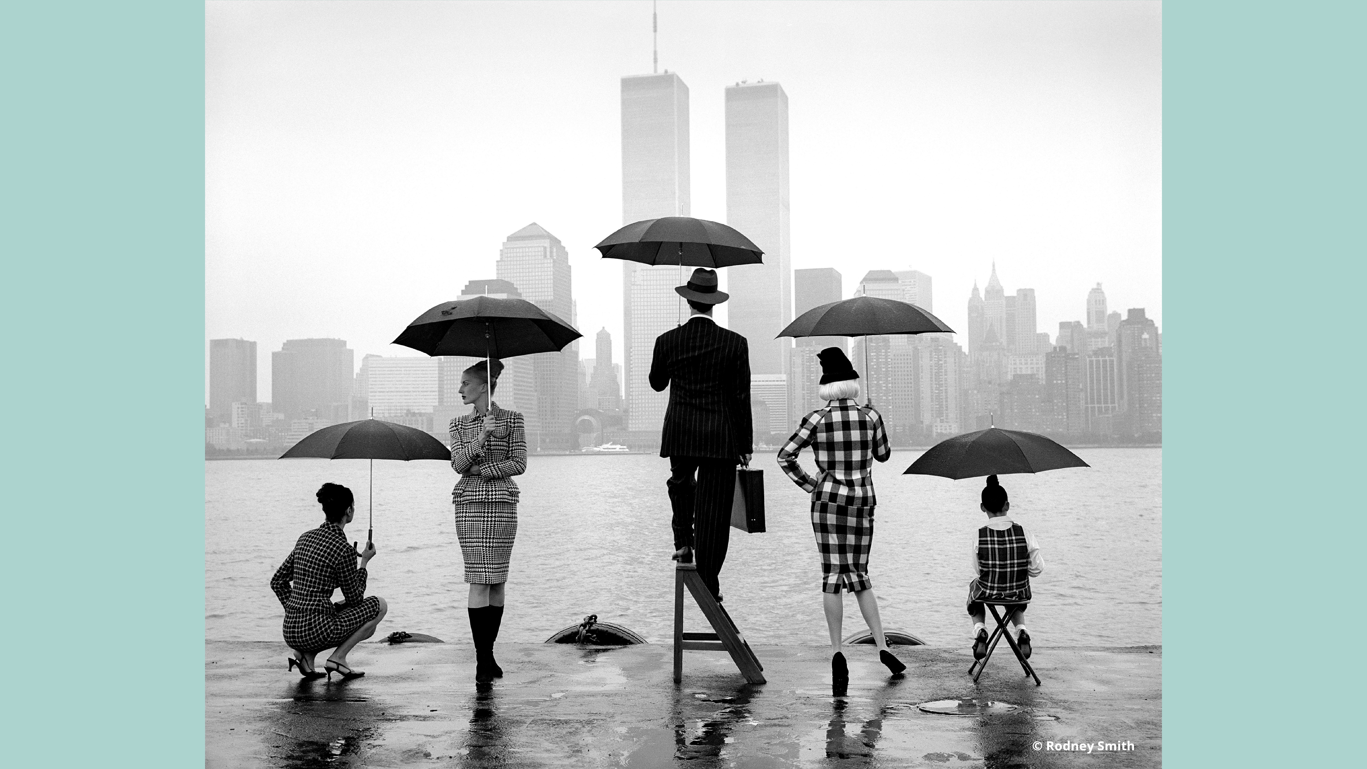 Fotografia di Rodney Smith che ritrae un gruppo di persone sotto la pioggia, con lo skyline urbano a fare da sfondo