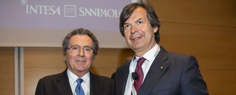 L’immagine che accompagna la News sulle dichiarazioni dell’Assemblea ritrae il Presidente di Intesa Sanpaolo, Gian Maria Gros-Pietro, a fianco del CEO Carlo Messina. Vestono entrambi in abiti formali, alle loro spalle è visibile la porzione di uno schermo su cui è riprodotto il logo della Banca